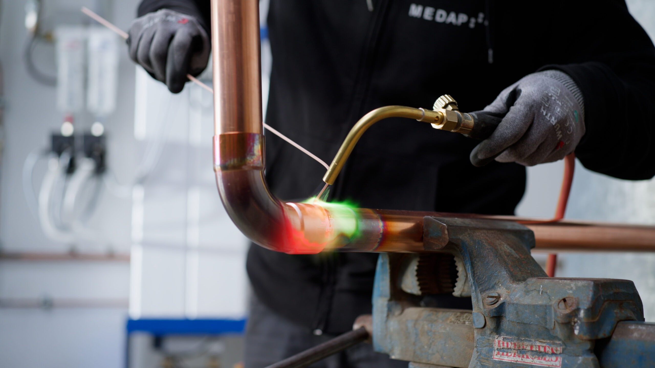Kupferrohr wird mit Brenner hartgelötet; Arbeitsstelle glüht.