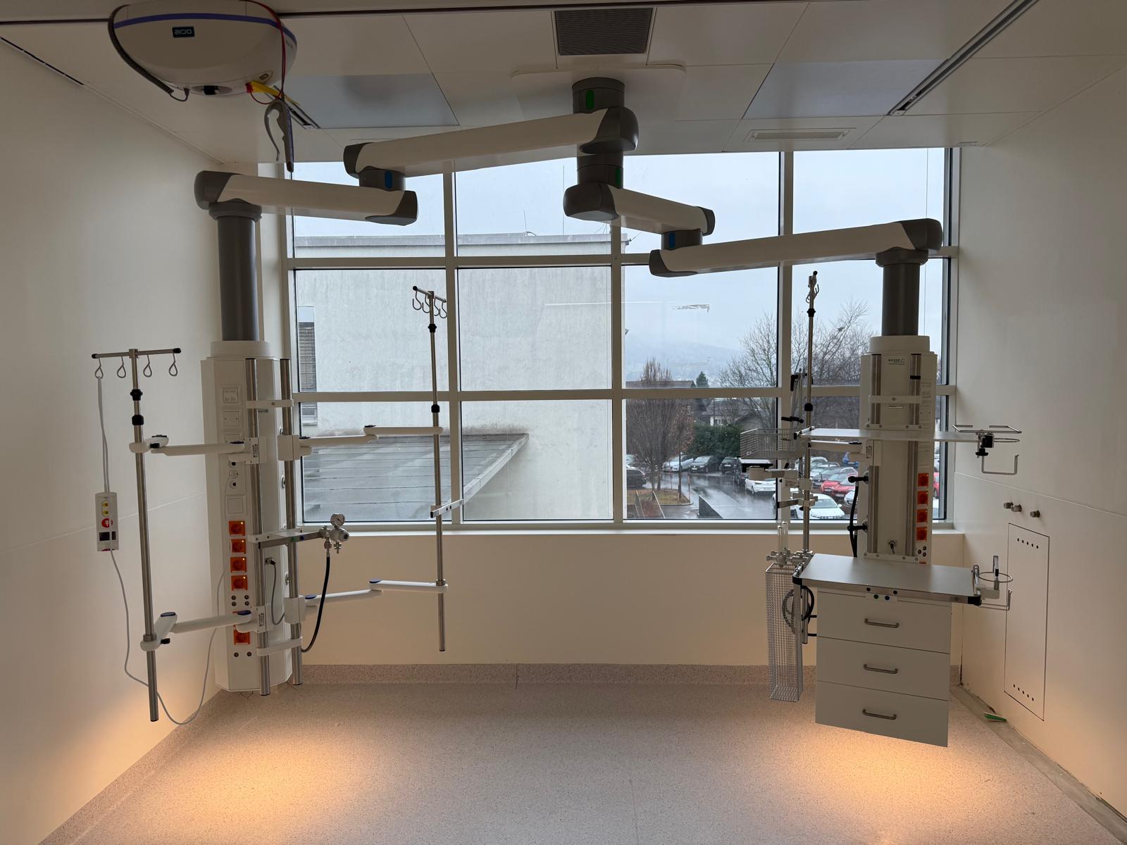 Patientenzimmer mit zwei medizinischen Deckenversorgungseinheiten an Schwenkarmen, Gas- und Stromanschlüssen sowie Infusionsständern.